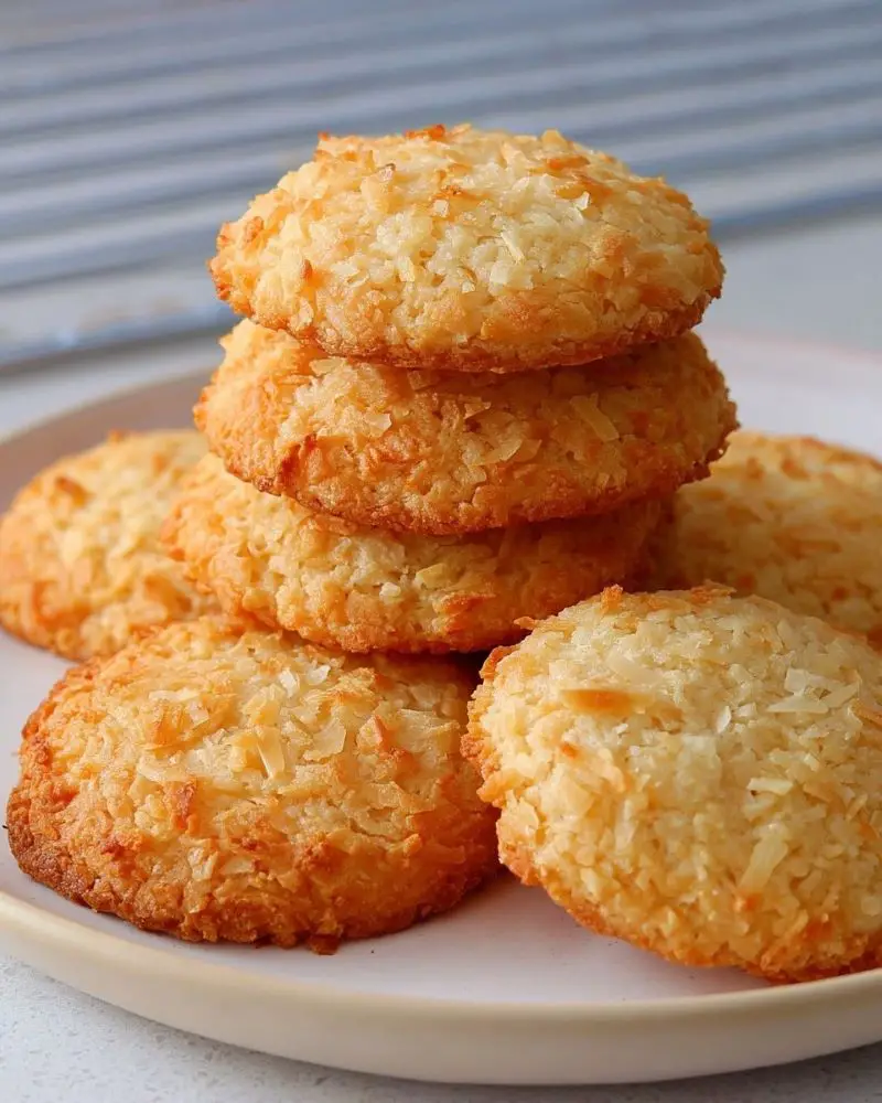 ## **Introduction**
There’s something wonderfully nostalgic about Coconut Cookies — the kind that fill the kitchen with a warm, buttery aroma that reminds you of cozy afternoons and family gatherings. These soft, lightly crisp cookies were a staple in my home growing up, always appearing at bake sales, holiday trays, and after-school snacks. Every bite brings back memories of sneaking warm cookies off the cooling rack before anyone noticed.
What I love most about this Coconut Cookies recipe is how simple, comforting, and timeless it is. Whether you’re baking a quick treat for the kids, preparing something sweet for a party, or just craving an easy homemade dessert, these cookies always hit the spot. They’re rich, tender, and full of coconut flavor — truly a treat for any season.
---
## **Why You’ll Love Coconut Cookies**
* **Crisp on the outside, soft inside** — the perfect texture combination.
* **Simple pantry ingredients** — nothing fancy or hard to find.
* **Quick to make** — ready in just about 30 minutes.
* **Great for gifting** — they pack beautifully and stay fresh.
* **Customizable** — add chocolate chips, nuts, or spices.
* **Kid-friendly and freezer-friendly** — perfect for storing and snacking later.
---
## **Ingredients You’ll Need**
* **1 cup (226g) unsalted butter, softened**
*Softened butter creates a tender, melt-in-your-mouth texture. Use cold butter if you prefer crispier cookies.*
* **¾ cup (150g) granulated sugar**
*Adds structure and sweetness.*
* **½ cup (65g) powdered sugar**
*Gives the cookies a softer crumb and lighter texture.*
* **1 large egg**
*Binds the dough and adds richness.*
* **1 teaspoon vanilla extract**
*For warm, classic flavor.*
* **2 cups (250g) all-purpose flour**
*Spoon and level to avoid overly dense cookies.*
* **1 teaspoon baking powder**
*Helps the cookies rise slightly and stay soft.*
* **½ teaspoon salt**
*Balances sweetness and enhances the coconut flavor.*
* **1½ cups (120g) desiccated coconut**
*Gives the cookies their signature flavor and chewiness. Unsweetened works best.*
---
## **Step-by-Step Instructions**
1. **Preheat your oven to 350°F (175°C)**
* Line two baking sheets with parchment paper to prevent sticking.
* If your kitchen runs warm, pop the prepared sheets in the fridge while mixing the dough to help the cookies hold their shape.
2. **Cream the butter and sugars**
* In a large bowl, beat together the softened butter, granulated sugar, and powdered sugar.
* Mix until light, pale, and fluffy — about 2–3 minutes.
* *If the mixture looks slightly grainy at first, don’t worry. Keep beating until smooth.*
3. **Add the egg and vanilla extract**
* Mix until well combined and silky.
* Scrape the sides of the bowl to ensure everything blends evenly.
4. **Combine the dry ingredients**
* In a separate bowl, whisk together the all-purpose flour, baking powder, and salt.
* This step ensures the leavening agent is evenly distributed.
5. **Add the dry mixture to the wet mixture**
* Gradually add the flour mixture into the butter mixture.
* Mix just until combined — *avoid overmixing to keep the cookies tender.*
6. **Fold in the desiccated coconut**
* Use a spatula or spoon to incorporate the coconut evenly throughout the dough.
* The dough will be slightly thick — that’s exactly what you want.
7. **Shape the cookies**
* Roll the dough into small balls, about 1 inch in diameter.
* Place them on the prepared baking sheets, leaving space between each cookie.
* *If the dough feels sticky, chill it for 10–15 minutes before shaping.*
8. **Flatten gently**
* Lightly press each dough ball with your palm or the bottom of a glass.
* These cookies don’t spread much, so this step helps them bake evenly.
9. **Bake for 12–15 minutes**
* Bake until the edges are lightly golden and the tops look set.
* The centers may seem soft — *don’t worry; they firm up as they cool.*
10. **Cool the cookies**
* Let the cookies rest on the baking sheet for 5 minutes.
* Move them to a wire rack to cool completely before serving.
**Prep Time:** 15 minutes
**Cooking Time:** 15 minutes
**Total Time:** 30 minutes
**Servings:** 24 cookies
**Calories:** ~190 kcal each
---
## **Serving and Storage Tips**
### **How to Serve Coconut Cookies**
These Coconut Cookies are delicious warm, but they’re equally lovely once cooled. Serve them with:
* A cup of tea, coffee, or cold milk
* A holiday cookie platter
* Ice cream — crumble a few cookies on top for texture
* A quick dessert for lunchboxes or after-dinner treats
They’re also perfect for gifting. Place them in a tin or clear gift bag tied with ribbon for an easy homemade present.
### **How to Store Coconut Cookies**
* **Room Temperature:**
Store in an airtight container for up to **1 week**.
* **Refrigerator:**
Not necessary, but can extend freshness by another few days.
* **Freezer (Baked Cookies):**
Freeze in a single layer, then move to a freezer-safe bag for up to **3 months**.
Thaw at room temperature.
* **Freezer (Cookie Dough):**
Roll into balls and freeze raw dough for easy future baking.
Bake straight from the freezer — just add 1 extra minute.
---
## **Helpful Notes**
* **Want crispier cookies?** Use cold butter instead of softened and flatten the dough balls a bit thinner.
* **Prefer thicker, softer cookies?** Chill the dough for 30 minutes before baking.
* **Add-ins that taste amazing:** White chocolate chips, chopped almonds, lime zest, cinnamon, or toasted coconut.
* **Make them gluten-free:** Use a 1:1 gluten-free baking flour blend.
* **Make them dairy-free:** Substitute vegan butter — choose a firm stick variety for best texture.
* **Too crumbly?** Add 1–2 teaspoons of milk until the dough comes together.
---
## **Frequently Asked Questions**
1. **Can I freeze Coconut Cookies?**
Yes! Both the baked cookies and the unbaked dough freeze extremely well for up to 3 months.
2. **What if I don’t have desiccated coconut?**
You can use finely shredded unsweetened coconut. Avoid large flakes unless you pulse them briefly in a food processor.
3. **Why did my cookies spread too much?**
Your butter may have been too soft. Try chilling the dough before baking.
4. **Can I reduce the sugar?**
You can reduce both sugars by up to ¼ cup without major texture issues.
5. **Can I make these cookies without eggs?**
Yes — replace the egg with 3 tablespoons of milk or ¼ cup applesauce.
---
## **Final Thoughts**
These Coconut Cookies are one of those recipes I return to again and again — simple, dependable, and always delicious. Every time I test and tweak the recipe, I’m reminded why it has stayed in my collection for years. It’s the kind of no-fuss treat that brings comfort and joy with every bite, whether you’re making them for a loved one or treating yourself to something sweet.
I hope this recipe becomes a favorite in your home, too. If you bake a batch, be sure to share your experience — I love hearing your stories, swaps, and serving ideas. Happy baking!